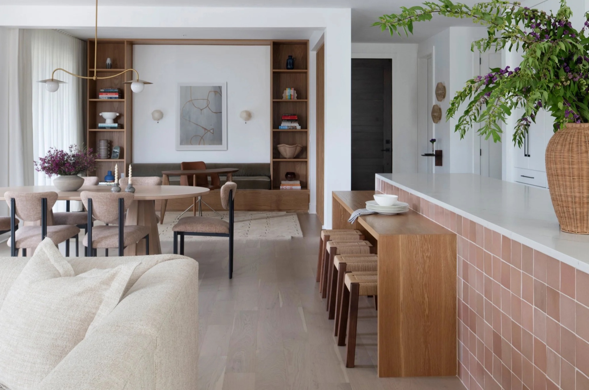 An open-plan kitchen and dining room with a terracotta-tiled island, oak joinery and woven stools, designed by Carrie Moore Interior Design.