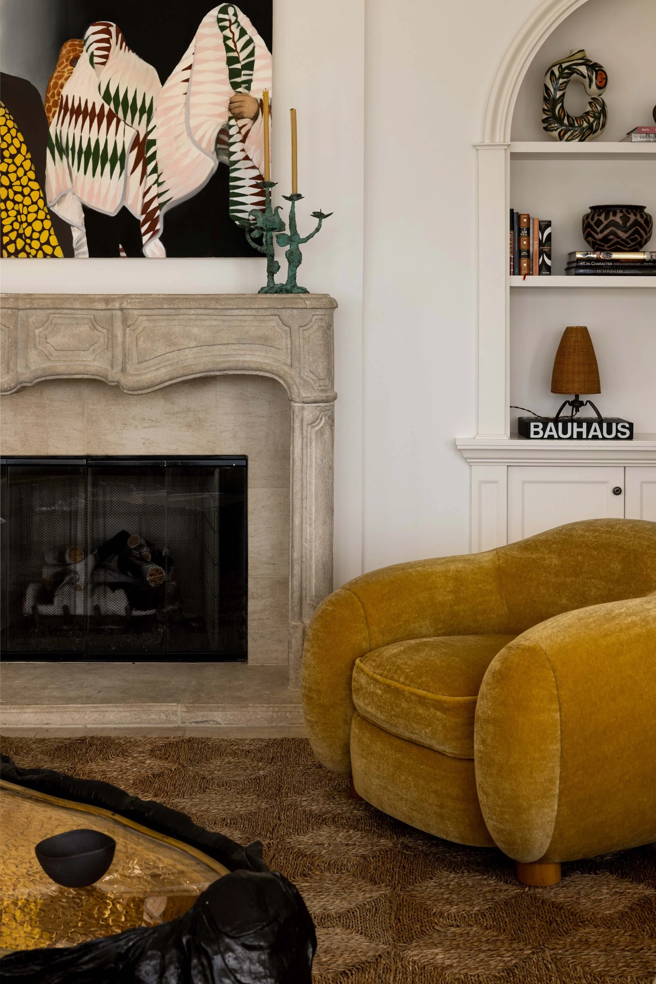 A living room with a deep sectional, sculptural bouclé chairs and layered stone-topped tables, designed by Studio Montemayor.