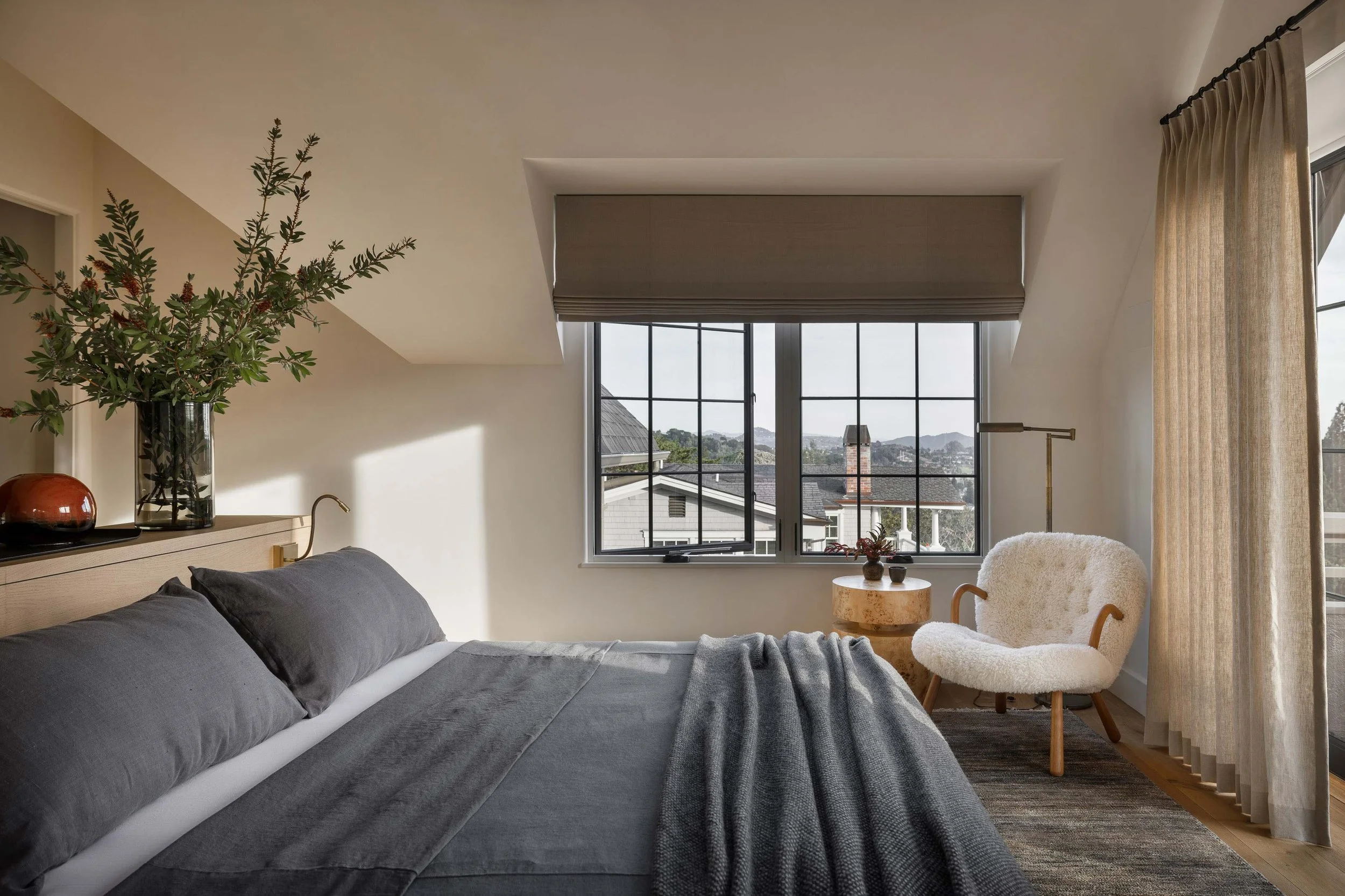 A bedroom with a limewashed headboard wall, oak panelling and a bronze pendant, designed by Studio Montemayor.